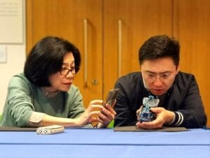 Handling Session at the British Museum: a man on the right examines a ceramic piece, a lady on the left takes a photograph of it