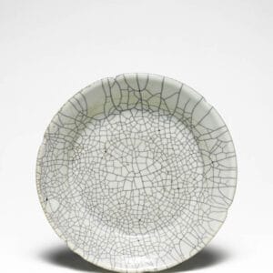 C.6-1968. Description Stoneware dish, with a thick, very pale greyish green opaque glaze with a dark grey fine crackle. Kuan type. The dish has a wide base and straight slanting sides. Six depressions in lip to represent flower petals. Convex central surface. The body is exposed at one place on the lip, and burnt reddish brown Short, glazed, tapering foot with unglazed rim burnt dark reddish brown. Glazed base. Bequeathed by Mrs Walter Sedgwick, 1968, through the National Art Collections Fund. From the Fitwilliam Collection